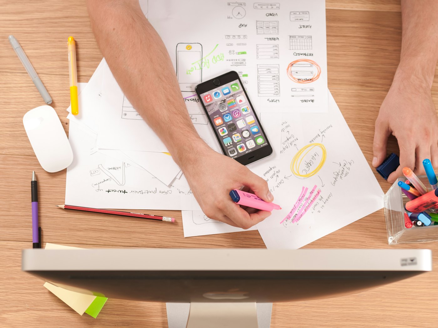 Hands planning content on paper beside a phone